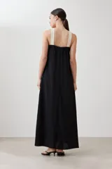 Maxi vestido negro con escote halter cruzado en color crema.