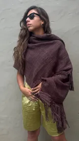Ruana artesanal tejida en telar con lana merino de alta calidad, color marrón chocolate obtenido con teñido natural. Presenta un tejido grueso y textura visible, con flecos largos en el borde inferior.