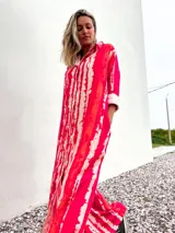 Vestido camisero largo con estampado batik en tonos rojo y beige, con cuello camisero y mangas largas con puños.
