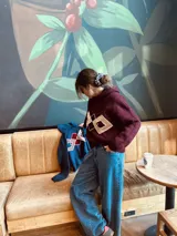 Sweater tejido color borgoña con cuello alto y diseño geométrico en el pecho en color crema.