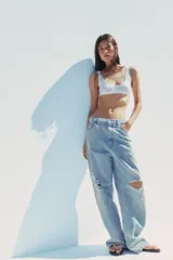 Pantalón de jean celeste claro, corte baggy, tiro medio, largo hasta el tobillo y con roturas grandes en ambas piernas.