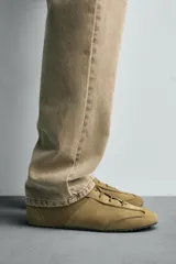 Zapatilla de cordones color beige, con capellada de cuero serraje, horma redonda y suela ultrafina.