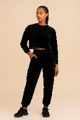 Conjunto deportivo negro de terciopelo compuesto por un buzo cropped de manga larga y un pantalón cargo con cintura ajustable y bolsillos laterales.
