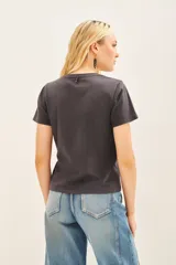 Remera básica de jersey color gris oscuro, con escote redondo y manga corta. Presenta bordados de corazones y estrellas doradas en el frente.