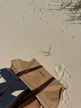 Bolso tipo tote de lona color beige con asas de cuero marrón.