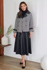 Campera corta con estampado pata de gallo en blanco y negro, cuello y puños de cuero sintético negro, doble botonadura y corte holgado.