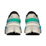 Championes de running On Running Cloudmonster 2, color crema con detalles en turquesa y verde. Presentan el logo de la marca en el lateral y suela con tecnología CloudTec.