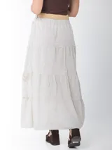 Falda larga de estilo campesino color crudo, confeccionada en algodón italiano con apliques florales al tono. Tiene cintura elastizada y cinto de rafia elastizado desmontable.