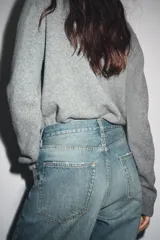 Chaqueta de punto color rosa pálido, con cuello redondo y cierre frontal de botones oscuros. Presenta mangas largas y un corte a la cintura.