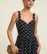 Vestido midi evasé sin mangas, confeccionado en tejido airflow con estampado de caracolas. Presenta escote corazón, breteles medianos con elásticos, recortes fruncidos en la cintura y en el bajo, y cierre lateral con cremallera invisible.