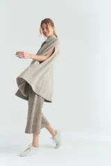 Capa larga color beige, con botones en la parte delantera y terminaciones envivadas.