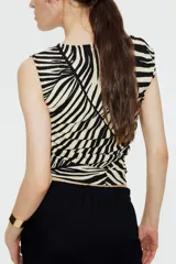 Top entallado de punto con estampado de cebra en blanco y negro, con escote barco, manga japonesa y costuras laterales fruncidas para un efecto drapeado suave.