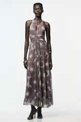 Vestido largo de tul con estampado floral en tonos marrón y celeste, cuello halter con lazada, escote pico cruzado, aberturas laterales en la cintura, frunces en la falda y forro interior.
