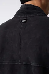 Buzo negro de frisa 100% algodón con medio cierre y bordado al tono. Tiene un lavado snow que le da un look gastado.
