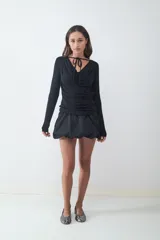 Minifalda negra de tiro bajo con silueta tipo globo, confeccionada en tejido técnico con cintura elástica oculta y bajo redondeado.