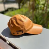 Gorra de cuero color dorado con etiqueta de cuero marrón con el logo de la marca "Bona".