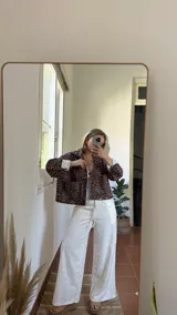 Campera corta de pana con estampado de leopardo, cuello camisero, cierre frontal con botones a presión y dos bolsillos delanteros. Interior forrado con tela a rayas verticales.