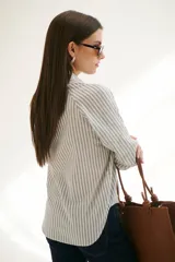 Camisa a rayas verticales color beige y blanco, con cuello clásico, botones marrones y mangas largas.