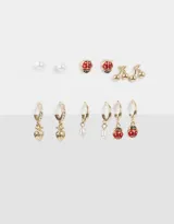 Set de seis pares de aros dorados con pasantes y argollas con dijes de frutas, perlas y strass.