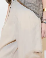 Pantalón de lino color gris gastado, con pinzas, silueta comba en piernas, bolsillos ojal en pierna izquierda y espalda. Largo hasta los tobillos y tiro medio.