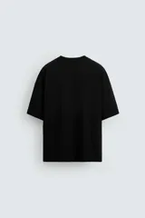 Camiseta negra de corte holgado, cuello redondo y manga corta. Estampado frontal con diseño abstracto en color blanco.