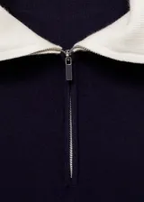 Jersey de punto fino color azul marino con cuello polo blanco y cierre de cremallera.