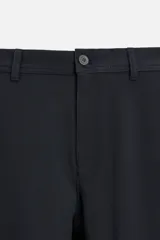 Pantalón slim fit negro confeccionado en tejido con elasticidad en ambas direcciones. Cuenta con bolsillos frontales y traseros de vivo con botón. Cierre frontal con cremallera y botón.