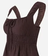 Blusa blanca con breteles anchos y escote cuadrado, detalle de lazo ajustable en el centro del busto y volado en el ruedo. El tejido es texturizado y ligero.