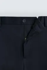 Pantalón de vestir azul marino, de corte recto, con bolsillos laterales y traseros. Se ajusta a la cintura con cinturón de cuero marrón.
