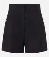 Short color beige de cintura alta, confeccionado en tejido plano con estructura sastre, con bolsillos laterales con tachuelas metalizadas.