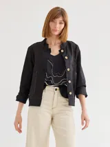 Chaqueta color marrón claro de lino y algodón, con cuello mao, cierre frontal con botones de madera y bolsillos laterales.