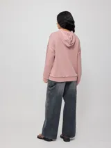 Canguro gris con capucha corta, bolsillo tipo canguro y parche con logo de la marca Rusty en el pecho. Tiene efecto lavado y costuras a la vista.