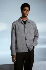 Sobrecamisa gris de tejido suave con cuello inglés, tapeta lisa, corte estándar, bolsillos superiores abiertos, abertura con botón en los puños, canesú en la espalda y bajo recto.