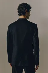 Blazer negro de corte slim fit, con solapas de muesca finas, ojal decorativo, botonadura sencilla, bolsillo superior insertado, bolsillos delanteros con solapa, dos bolsillos interiores, botones decorativos en los puños y abertura doble atrás. Forrado.