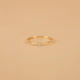 Anillo solitario de oro amarillo 18k con un brillante engarzado en 4 puntas y un anillo con esmeraldas engarzadas.