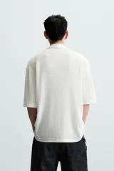 Camisa de manga corta con cuello bowling y calce relajado. Presenta un tejido con textura estructurada y efecto lavado, con cierre frontal de botones al tono.