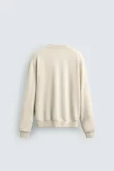 Sudadera color beige claro con cuello redondo y mangas largas.