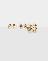 Set de tres pares de aros dorados: un par de aros tipo botón con forma irregular, un par de aros colgantes con forma de lágrima y un par de aros tipo argolla gruesa.