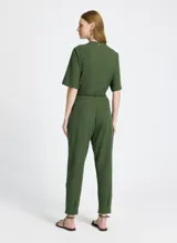 Pantalón jogger verde de tejido de punto con corte recto, cintura con trabillas y cordón ajustable con puntas de madera. Presenta bolsillos laterales con solapa y pespuntes.