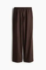 Pantalón marrón de algodón, corte holgado, tiro alto, cintura elástica fruncida con cordón ajustable, piernas anchas y bolsillos laterales.