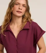 Blusa color borgoña de viscosa texturizada, con cuello, abotonada al frente, mangas cortas con dobladillo y lazo en la cintura.