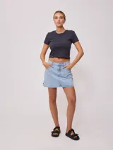 Minifalda de jean azul con bolsillos delanteros y traseros, tiro alto y corte recto.