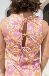 Top sin mangas con estampado floral en tonos rosa y naranja, con cuello redondo y espalda descubierta atada con tres lazos.