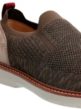 Zapato slip on color marrón de tejido de poliéster, con elástico en los laterales y detalle de cuero sintético en el talón.
