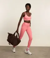 Top deportivo con copas removibles, confeccionado en microfibra color salmón. Presenta tiras elásticas cruzadas en la espalda con logo estampado.