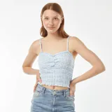 Top corto con tirantes finos, escote recto fruncido y estampado vichy celeste y blanco.
