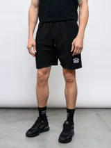 Bermuda deportiva negra de felpa con efecto lavado, con logo Umbro estampado en blanco en la pierna derecha.