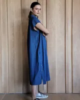 Túnica celeste de corte recto, con cuello camisero, mangas cortas, tajos laterales y cierre frontal con botones.