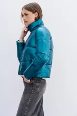Campera puffer metalizada color azul petróleo, con cuello alto, cierre frontal y bolsillos con cierre. Tiene ajuste interno en el ruedo.