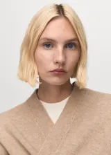 Abrigo largo de tejido de punto color beige, sin cierre, con cuello solapa y manga larga.